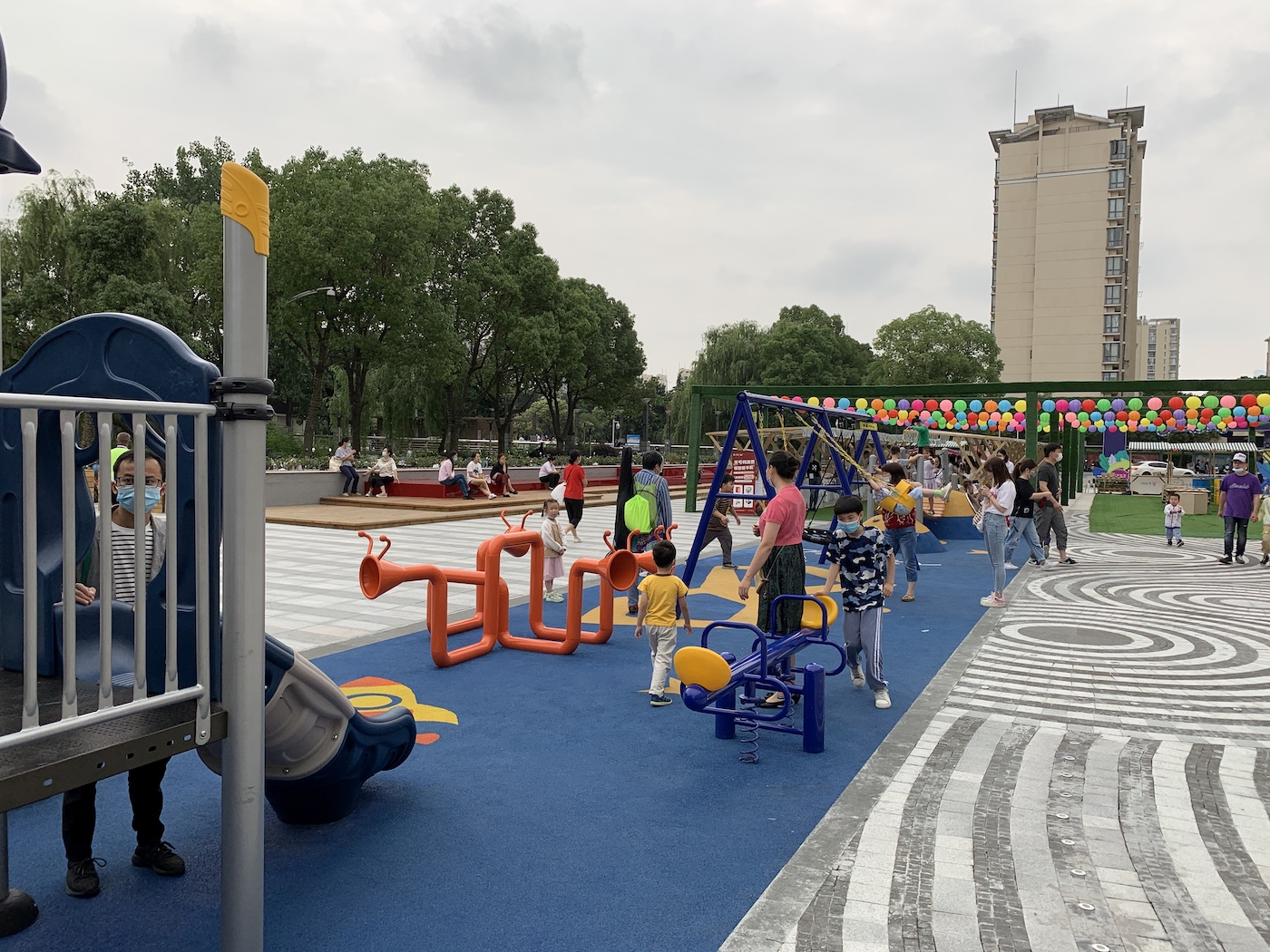 “A busy playground in Suzhou at the end of June. The colorful garlands in the background were part of an evening street market that was getting ready to open.”